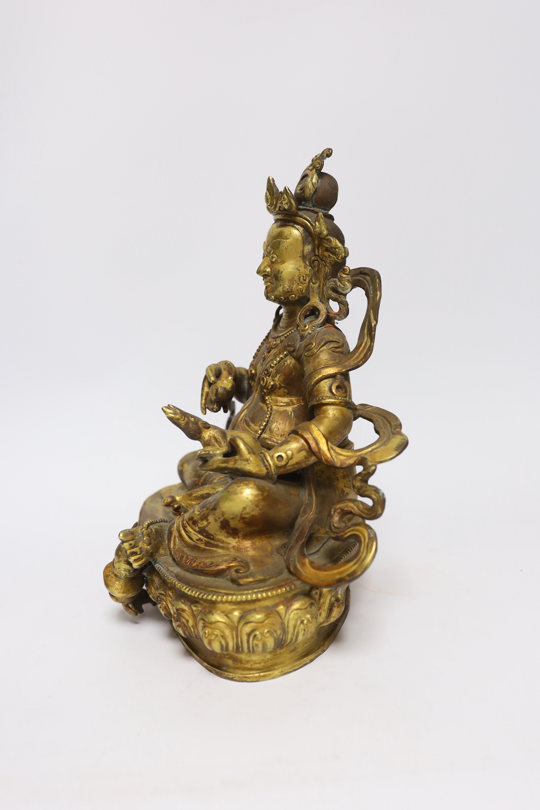 A large Sino-Tibetan gilt bronze seated figure of Jambhala, 28cm high